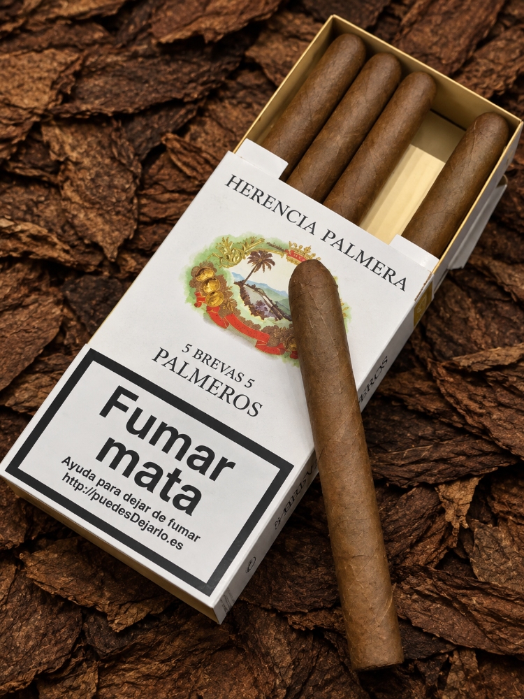 Herencia Palmera Palmeros Brevas pack and single cigar on tobacco leaves